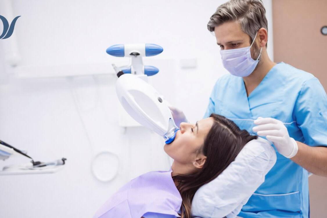 Dentist performing professional teeth whitening treatment using LED light on a patient in a modern dental clinic in Victoria